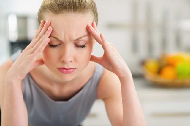 頭痛で頭を抱える女性