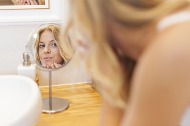 鏡でスキンケアチェックをする女性